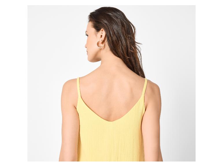 Vrouw met donker haar en oorringen, draagt een geel spaghettibandje topje, van achteren gezien.