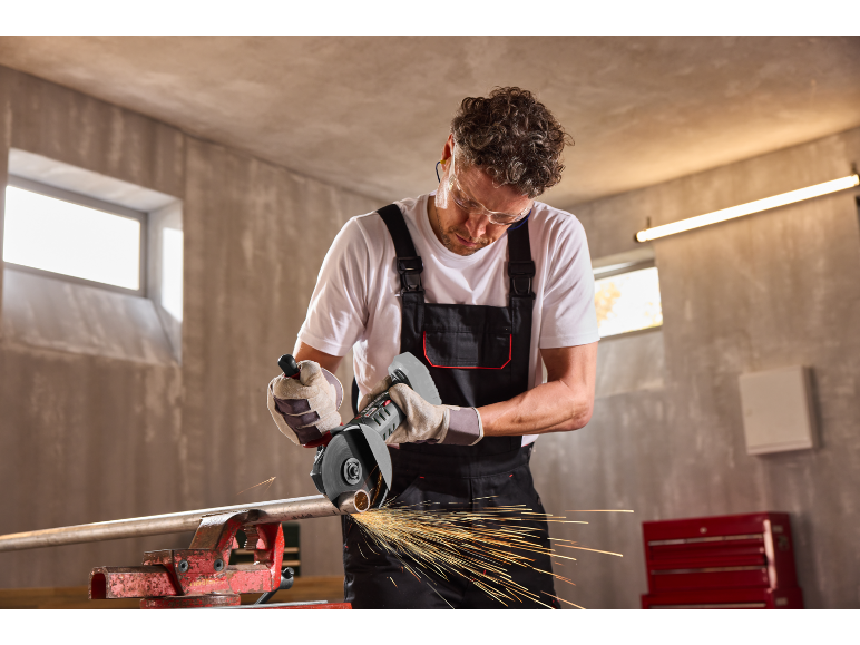 Man snijdt metalen pijp met haakse slijper, vonken vliegen.