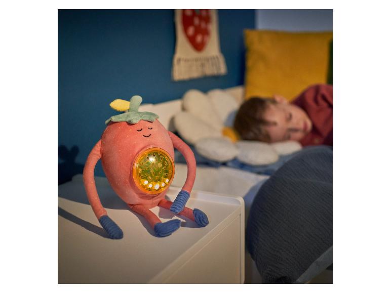 Pluche aardbeien-speelgoed met geïntegreerd licht naast een slapend kind.