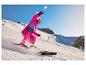 Kind in roze skipak en Crivit skihandschoenen aan het skiën.