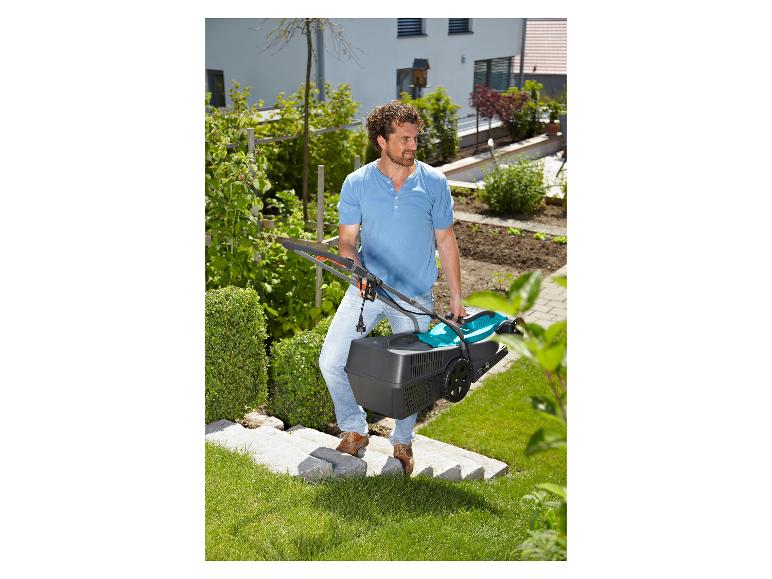 Man draagt grasmaaier de trap op in de tuin.