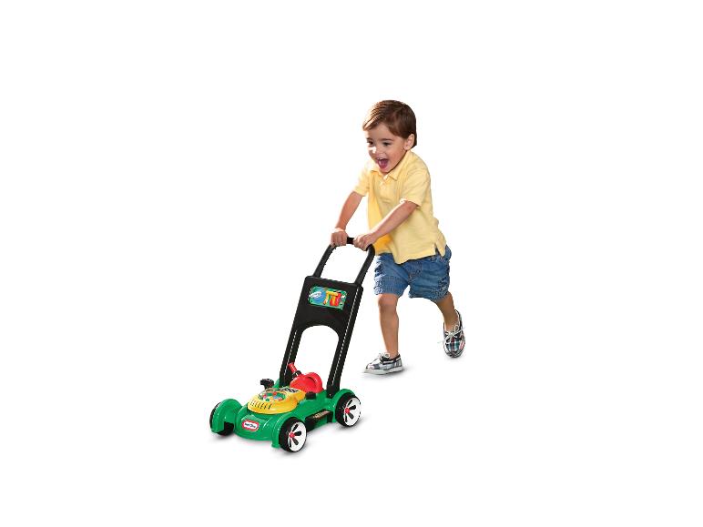 Blije jongen speelt met een groene Little Tikes speelgoedgrasmaaier.