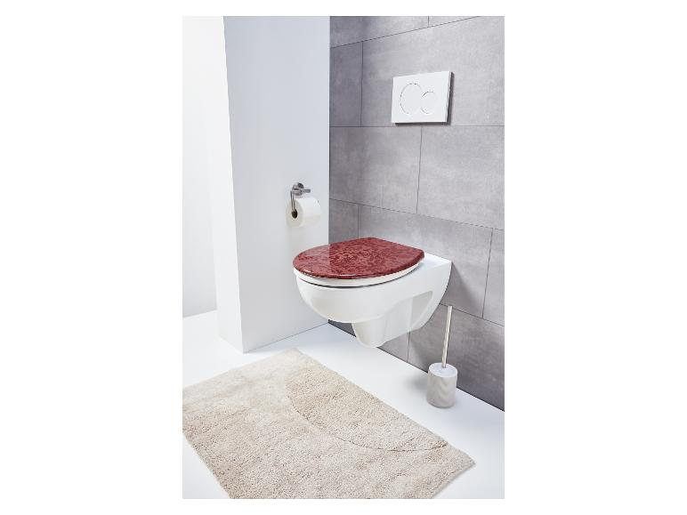 Toilet met rood toiletbril en kleed.