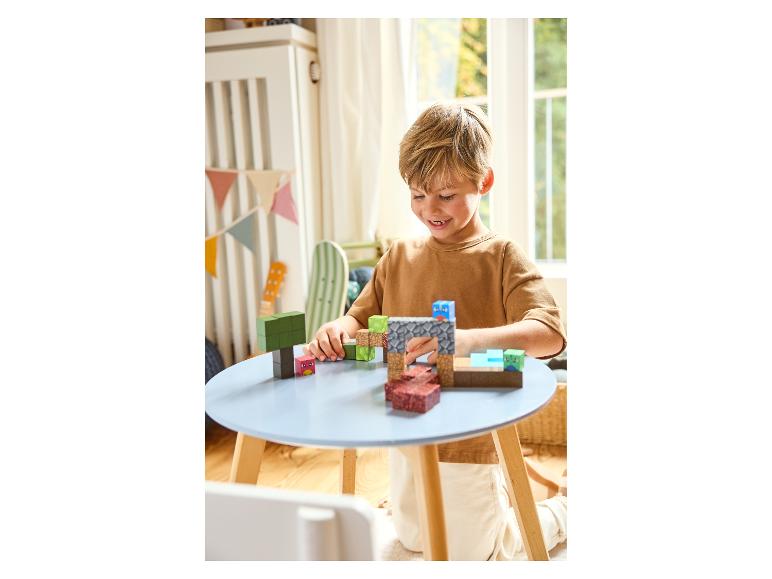 Lachende jongen speelt met Minecraft bouwblokken aan een blauwe tafel.