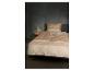 Beige beddengoed met geometrisch patroon op bed in slaapkamer met nachtlampje.