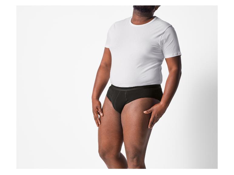 Een man draagt ​​zwarte onderbroeken en een wit T-shirt.