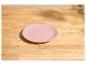 Roze bord op een lichte houten tafel met zonlicht en schaduwen.
