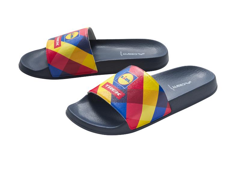 Twee blauwe slippers met kleurrijke geruite banden, één met de tekst 'TREK' en een logo.