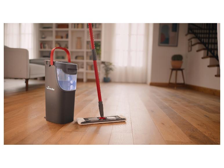 Dweil en emmer met wringsysteem in een woonkamer met houten vloer.