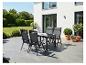 Tuinmeubelset: tafel en vier stoelen op een terras, omringd door groen.