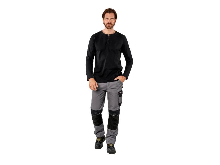 Man in zwart shirt met lange mouwen en grijze werkbroek met zwarte verstevigingen.