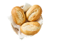 Drie versgebakken broodjes in een rieten mand, bekleed met een wit servet.
