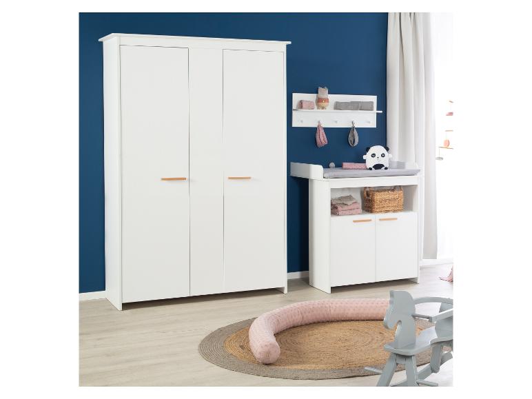 Witte babykamer met kledingkast, commode en speelgoed op een vloerkleed.