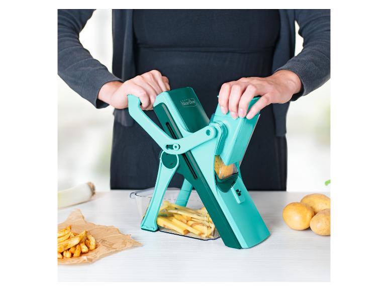 Vrouw gebruikt Nicer Dicer om aardappelen te snijden in de keuken, met frietjes ernaast.