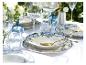 Elegante buitentafel met blauw-wit bloemendessin servies, gouden bestek en heldere glazen.