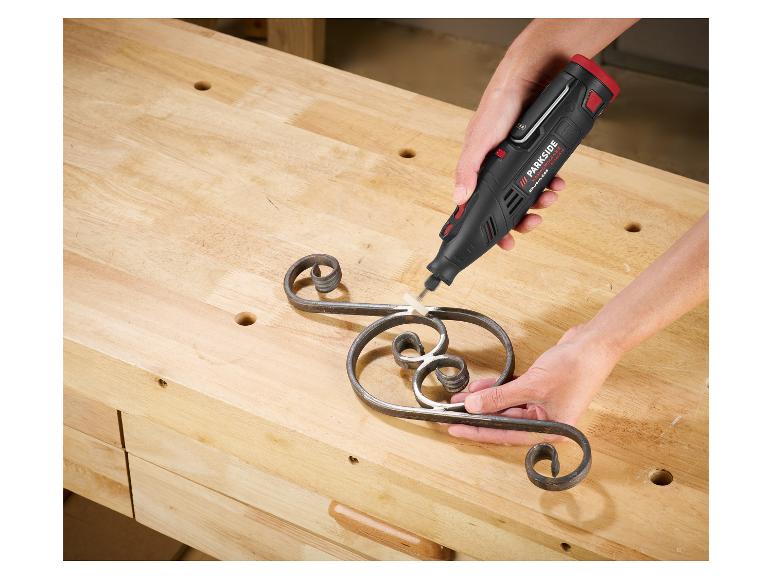 Een persoon gebruikt een Parkside roterend gereedschap om een metalen ornament op een werkbank te schuren.