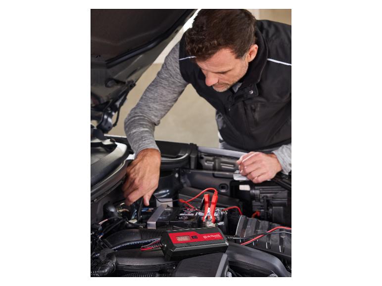 Man sluit een Ultimate Speed acculader aan op een auto.