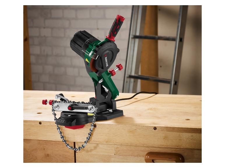 Elektrische kettingzaagslijper op een houten werkbank in een werkplaats.