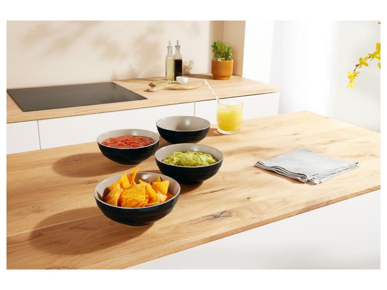 Drie keramische kommen met snacks op een houten tafel.