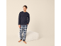 Man in marineblauwe pyjama en geruite broek, lachend.