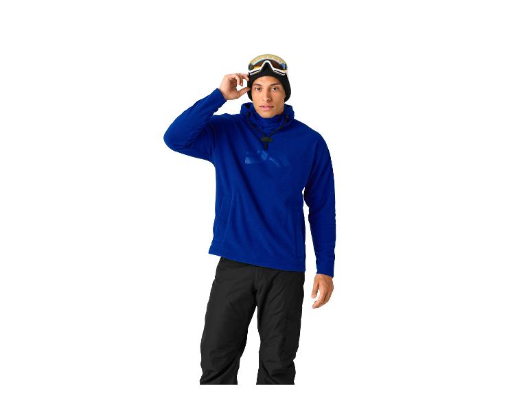 Man in blauwe hoodie en zwarte broek, met skibril op zijn hoofd.