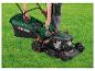 Persoon bevestigt grasopvangbak aan een Parkside benzinemaaier op groen gras.
