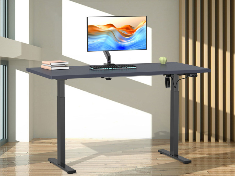 Een zwart, elektrisch verstelbaar bureau met een monitor en toetsenbord.