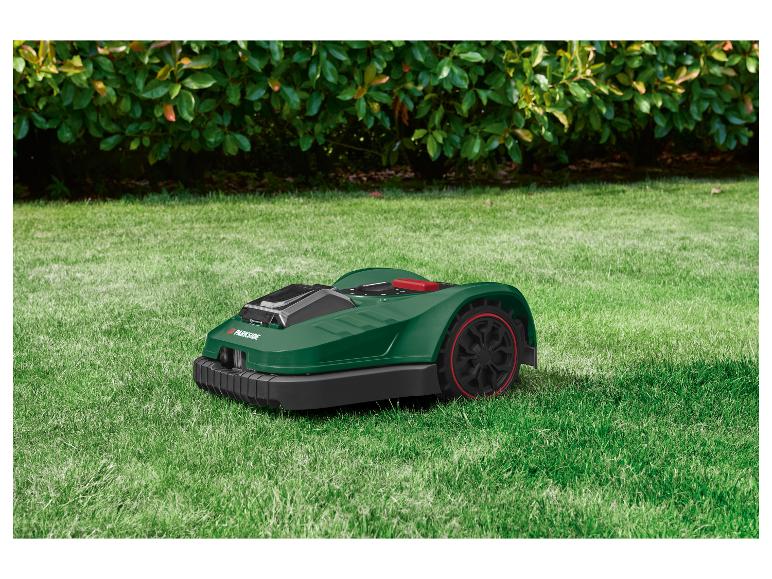 Groene Parkside robotmaaier op een gazon voor struiken.