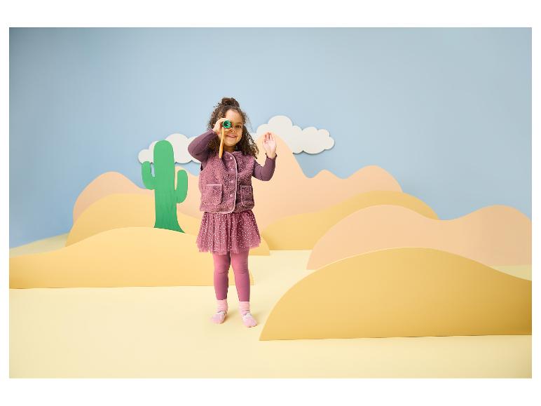 Meisje in paarse kleding met een verrekijker in een woestijnlandschap.