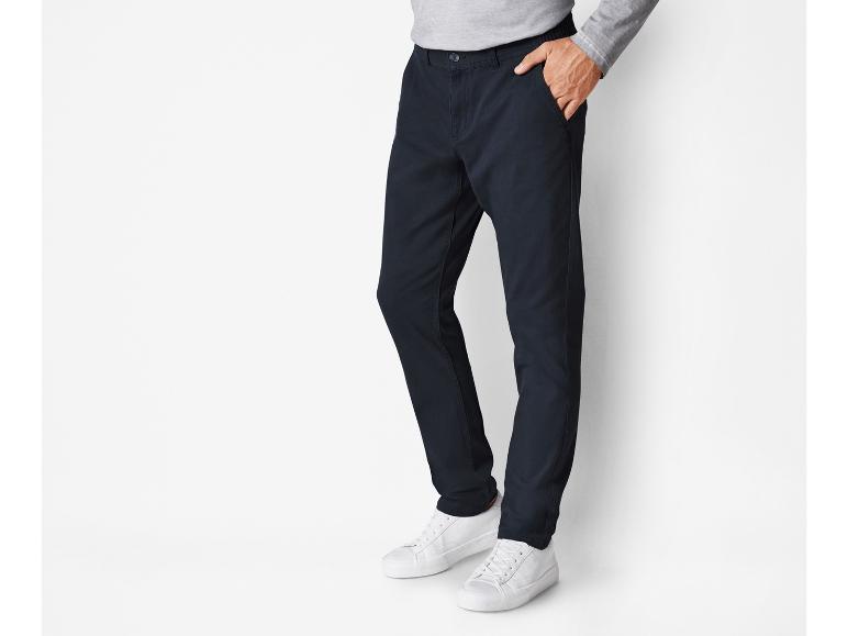 Een man draagt ​​donkerblauwe broek en witte sneakers.