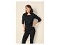 Vrouw in zwart thermoshirt en legging, lachend en ontspannen.