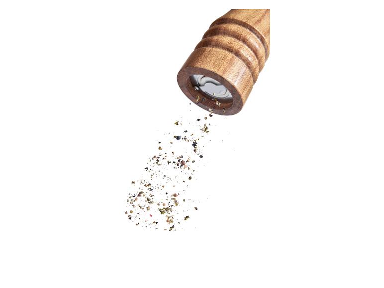 Houten pepermolen strooit peper.