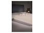 Opgevouwen beige hoeslaken op een bed, met een decoratieve lamp op de achtergrond.