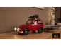 Rode speelgoedauto met kerstman en kerstboom op een houten plank.