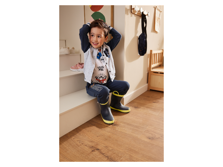 Jongetje zit op een trap met Paw Patrol kleding en laarzen.