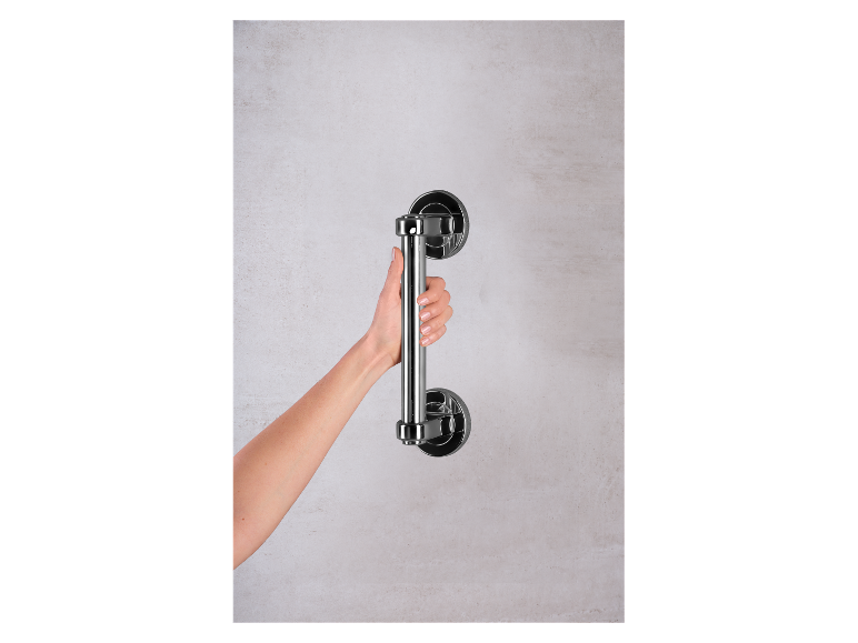 Een hand houdt een verchroomd metalen handvat op een muur vast.