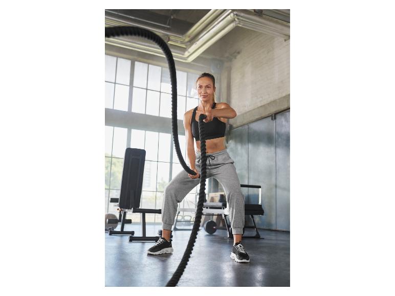 Vrouw in sportkleding gebruikt battle ropes in een sportschool.