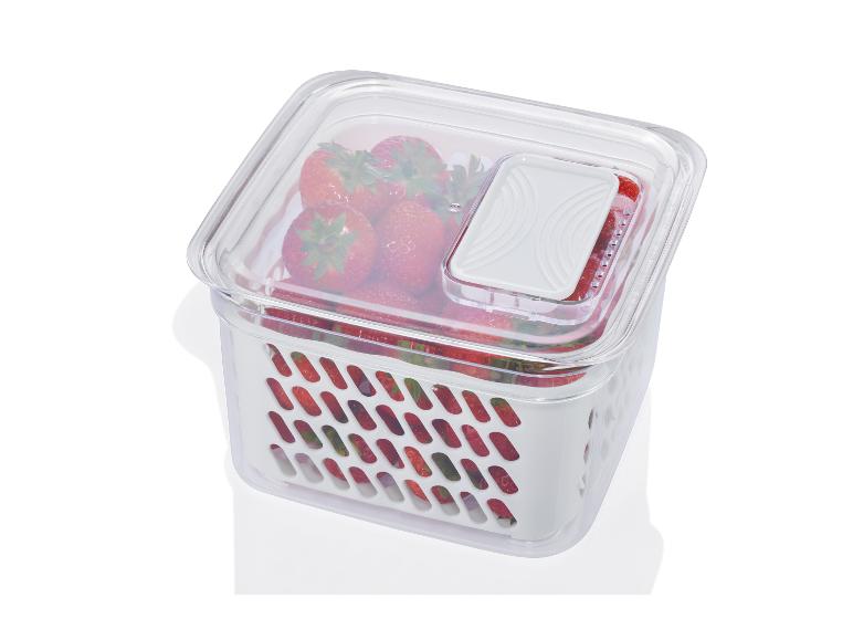 Een transparante opbergdoos met een roostervormige bodem, gevuld met aardbeien.