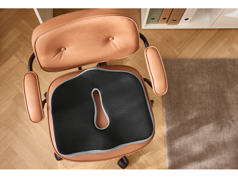 Ergonomisch kussen op bruine leren bureaustoel, bovenaanzicht.