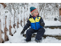 Lachend kind in ski-jas en sneeuwbroek zit op besneeuwde treden.