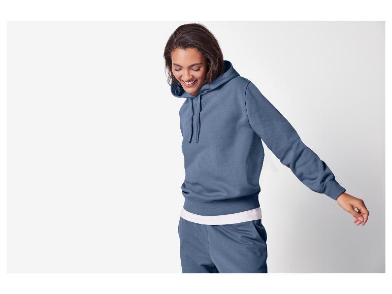Lachende vrouw in blauwe hoodie en joggingbroek
