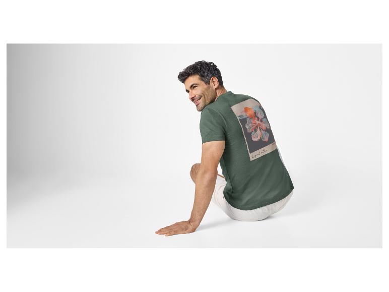 Man in een donkergroen T-shirt met bloemenprint en de tekst 'Original pattern' op de rug.