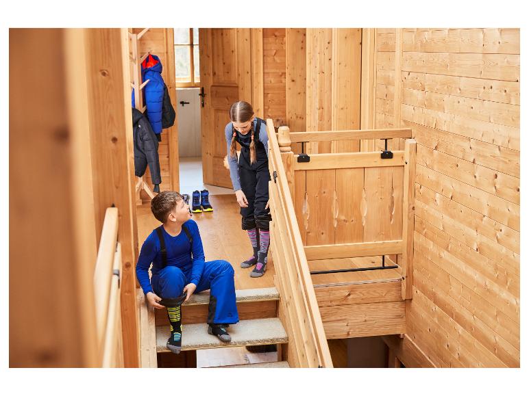 Twee kinderen in CRIVIT naadloos functioneel ondergoed maken zich klaar om te skiën.