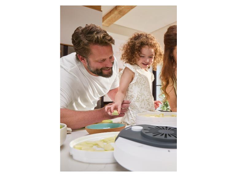 Gezin gebruikt een voedseldroger om appels te drogen.