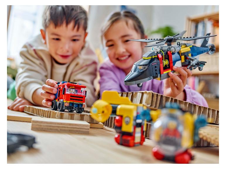 Twee kinderen spelen met bouwspeelgoed, waaronder een helikopter en een brandweerwagen.