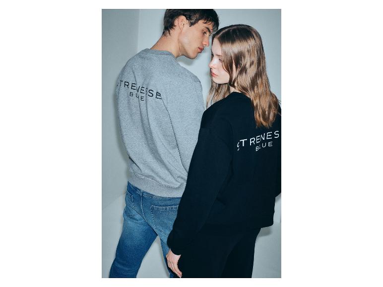 Twee jonge mensen dragen grijze en zwarte hoodies met tekst op de rug, blauwe jeans.