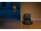 Robotstofzuiger met laadstation op een houten vloer, met een donkere kamer op de achtergrond.