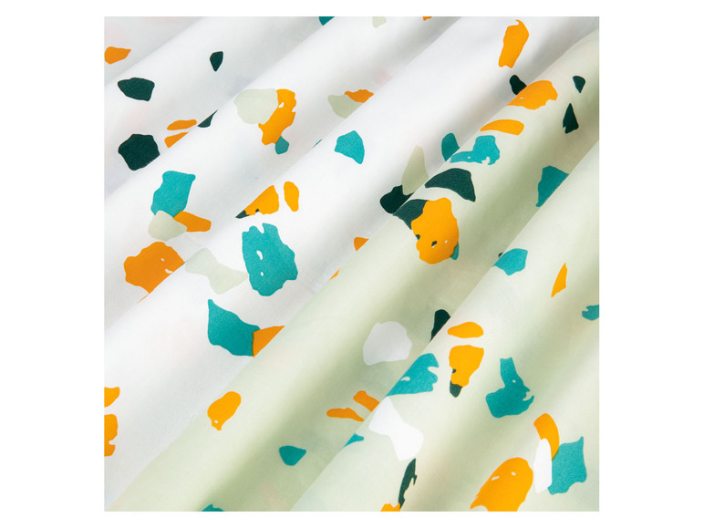 Witte stof met oranje, blauwe en groene stippen.