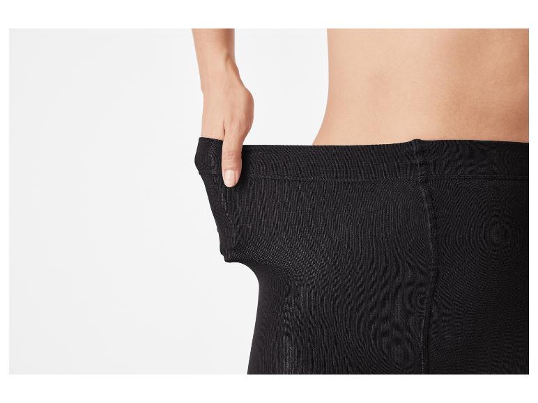 Persoon trekt aan de tailleband van een zwarte panty om elasticiteit te tonen.