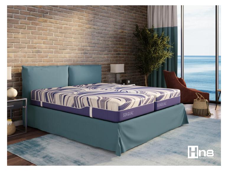 Slaapkamer met Hn8 Sequal bed, bakstenen muur en uitzicht op zee.